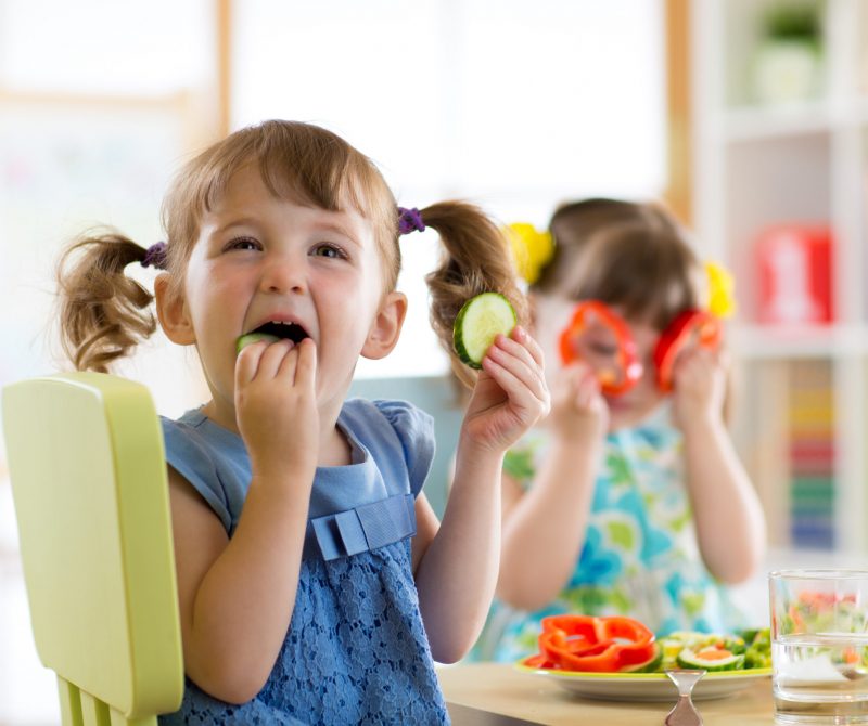 children kids eating vegetables in kindergarten or at home